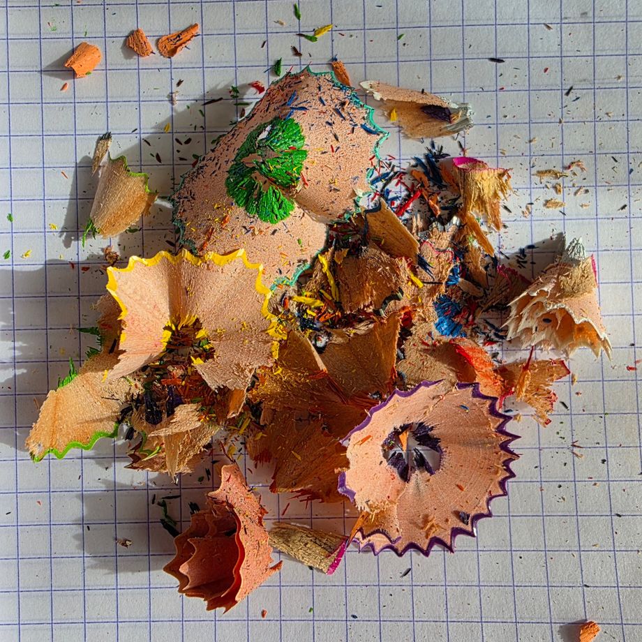 Copeaux de crayons de couleur sur une feuille quadrillée.