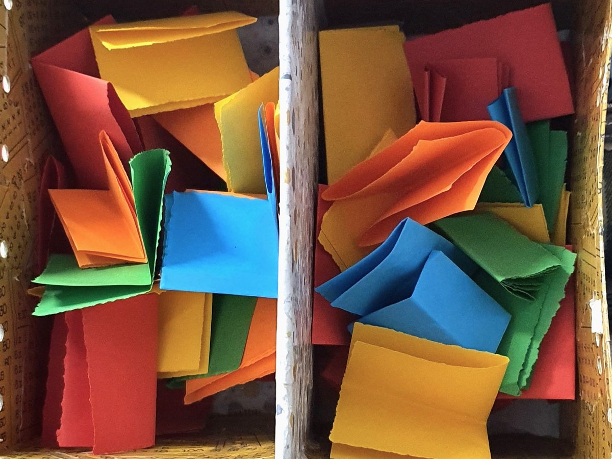 Une boîte à deux compartiments remplie de papiers de couleur pliés.
