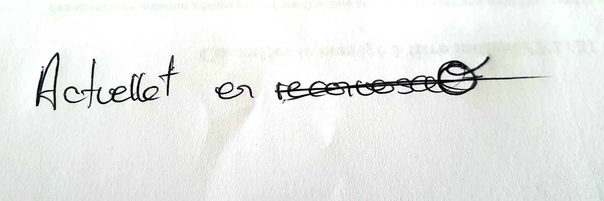 Sur une feuille blanche, écrit au stylo : « Actuellt en », suivi d’un mot barré d’un trait.